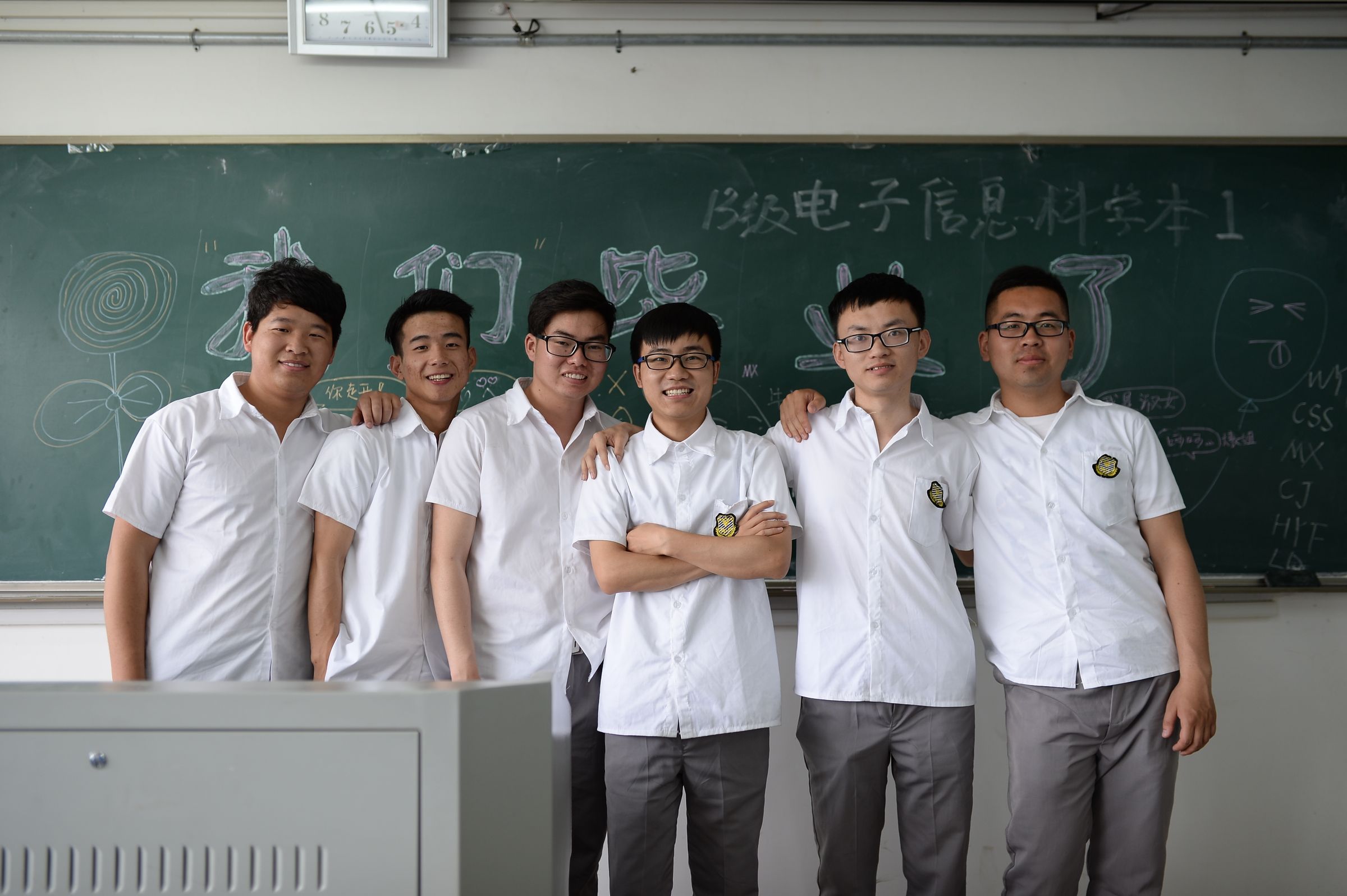 A class of students smiling in front of a blackboard.